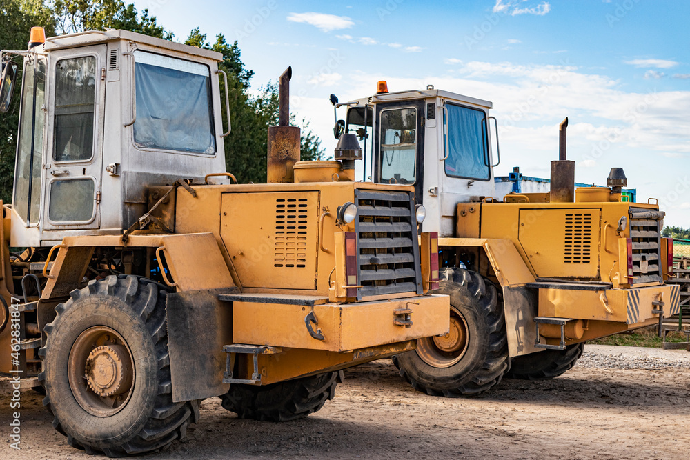 Two heavy wheel loaders are standing at a construction site. Equipment for earthworks, transportation and loading of bulk materials - earth, sand, crushed stone.