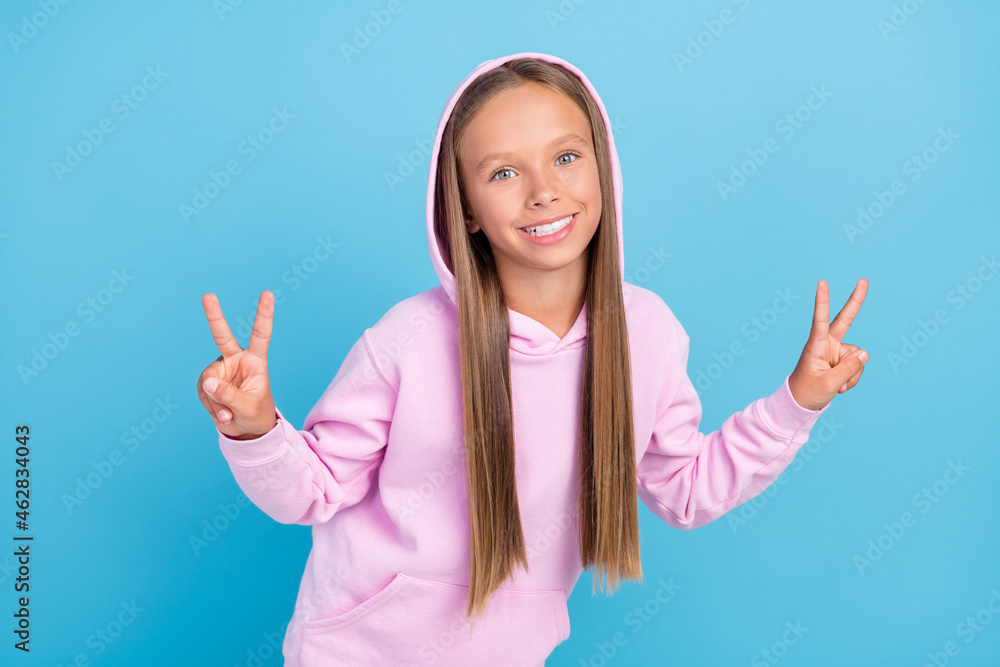 Photo of cool cheerful positive young little girl make fingers v-signs good mood isolated on blue color background Photo of cool cheerful positive young little girl make fingers v-signs good mood isolated on blue color background