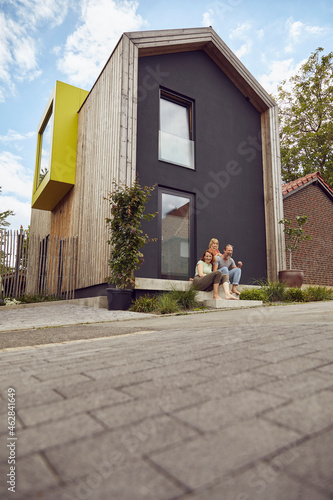 Family sitting on steps outside tiny house photo