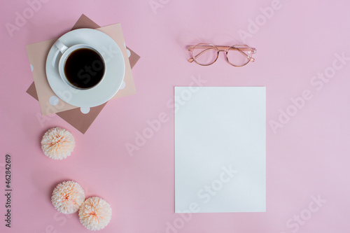 White note with pink flowers and coffee and glasses over pink background. 