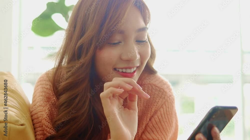 beautiful asian woman smiling happy at home in the living room Lying on the phone, making online video calls, chatting with friends. Modern communication technology concept, social distance. beautiful asian woman smiling happy at home in the living room Lying on the phone, making online video calls, chatting with friends. Modern communication technology concept, social distance.