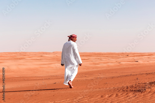 Bedouin walking in the desert, Wahiba Sands, oman photo