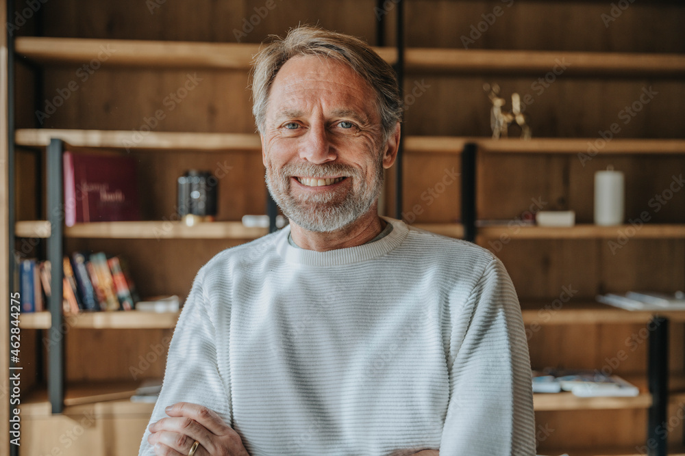 Smiling handsome man with gray eyes against shelf at home Smiling handsome man with gray eyes against shelf at home
