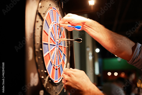 Close-up of man taking out darts from electronic dartboard photo