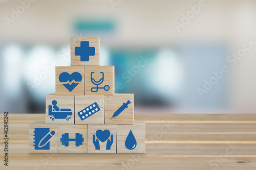 Wood block with healthcare medical icon on blurred background of emergency room in hospital. A symbol that represents comprehensive patient care.