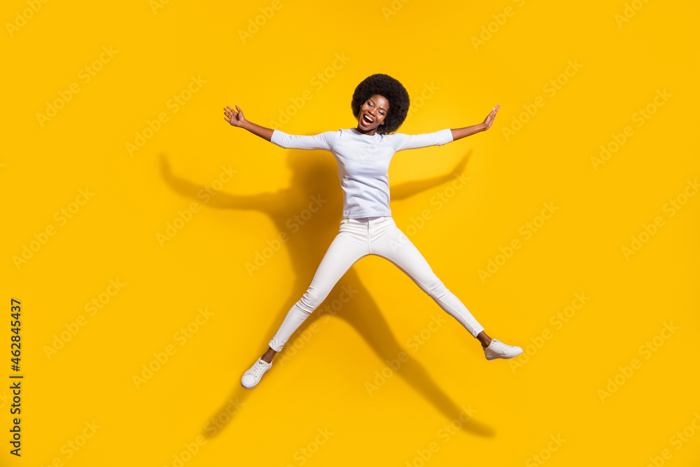 Full length photo of dark skin happy woman jump up star shape smile isolated on yellow color background