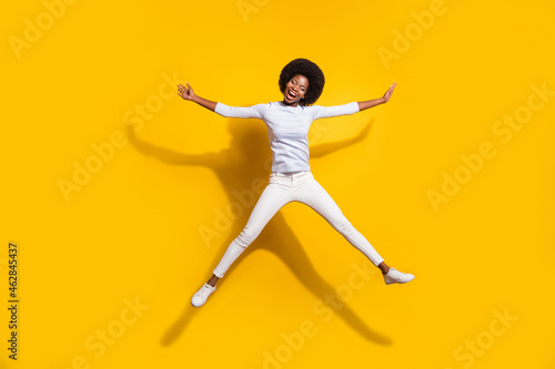 Full length photo of dark skin happy woman jump up star shape smile isolated on yellow color background © deagreez