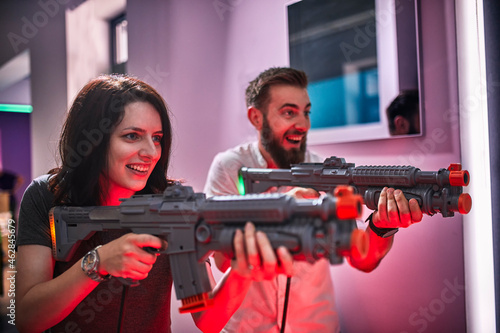 Happy couple playing and shooting with rifles in an amusement arcade photo
