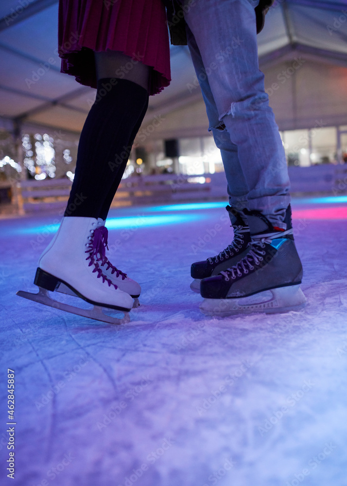 Legs of couple wearing ice skates standing on an ice rink