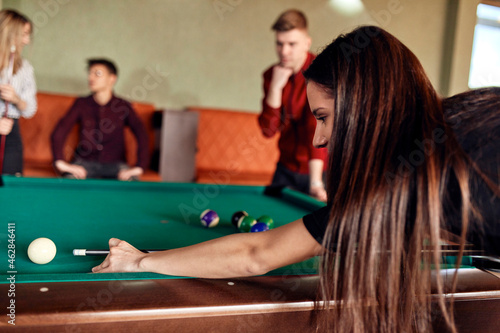Young woman playing billiards with friends photo