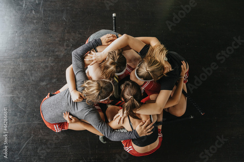 Girls huddling while crouching on floor in health club photo