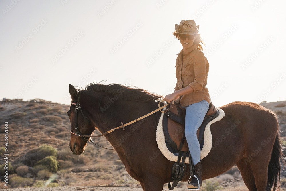 Young farmer woman riding her horse in a sunny day outdoor - Focus on face