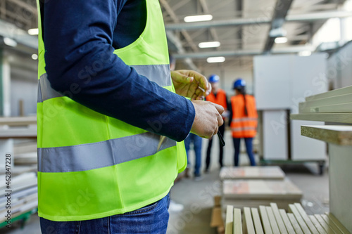 Close-up of worker wearing reflective vest in factory photo