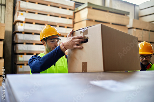 Worker carrying box in factory warehouse photo