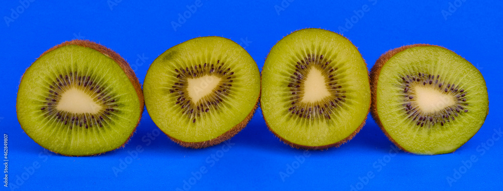 Fototapeta premium Sliced kiwi fruits on blue background