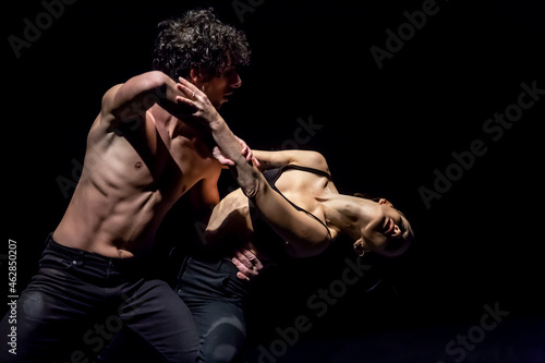 Male and femal dancer performing contemporary ballet on black stage