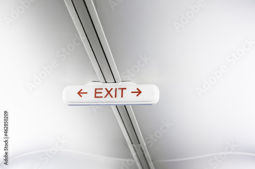 Exit sign on white airplane ceiling