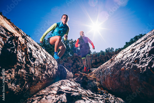 Mature couple running on logs against clear blue sky during sunny day