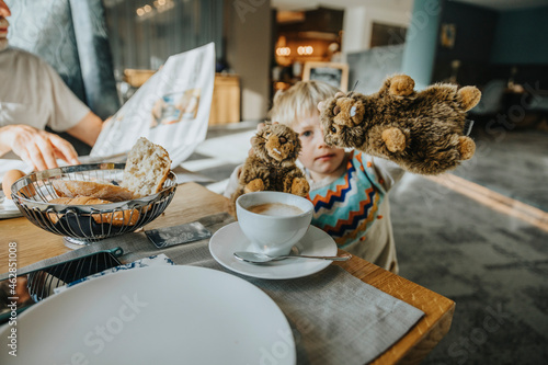 Boy showing Alpine Marmot toy at table in hotel room photo