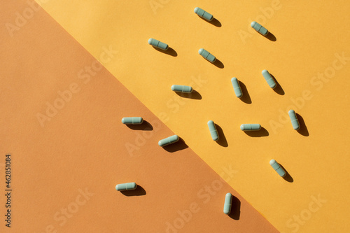 Scattered green capsules against a yellow and brown background photo