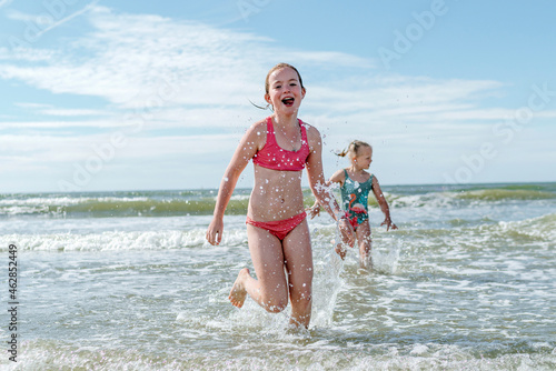 Girls running in water at beach on sunny day photo