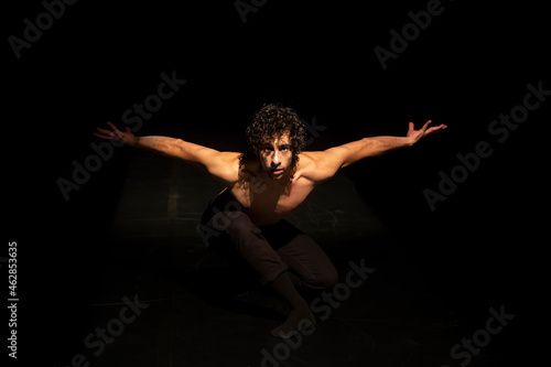 Male ballet dancer performing on black stage photo