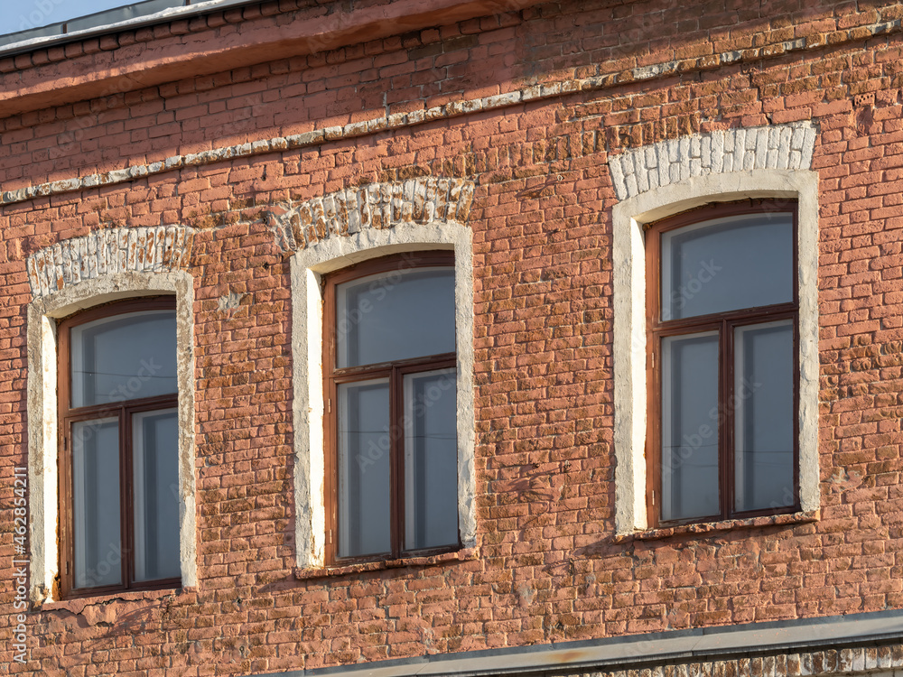 Three windows of the old mansion 19 century with brown bricks wall