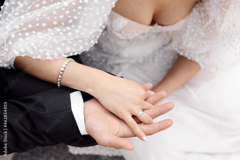 A young man, groom holds in his hand hand of his woman bride, bride in dress with open decolletage and wide sleeves. unrecognizable people. A young man, groom holds in his hand hand of his woman bride, bride in dress with open decolletage and wide sleeves. unrecognizable people.