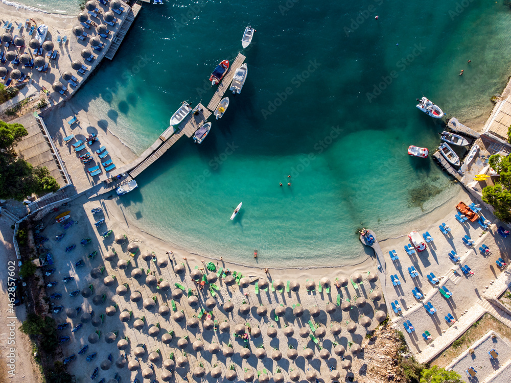Aerial drone view of exotic sandy beach at summer. Parasols and deck chairs on beach, view from above. Colorful sea water. 