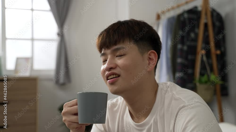 closeup shot of asian male looking into distance feeling refreshed and happiness after smelling his delicious coffee on a peaceful morning in the bedroom at home closeup shot of asian male looking into distance feeling refreshed and happiness after smelling his delicious coffee on a peaceful morning in the bedroom at home