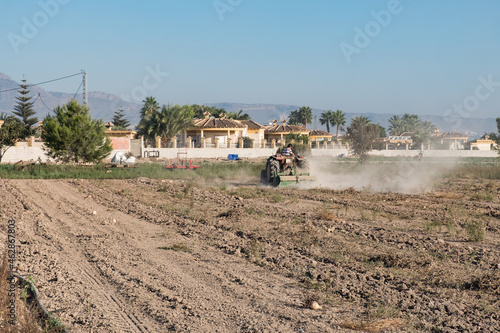 young farmer tilling the land with a tractor on his small plot of land. © aglcharro