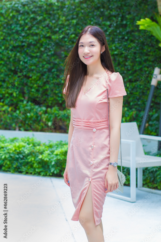 Young Asian professional business woman with long hair is smiling in the outdoors garden while looking at the tablet in her hand, work from anywhere concept. Young Asian professional business woman with long hair is smiling in the outdoors garden while looking at the tablet in her hand, work from anywhere concept.