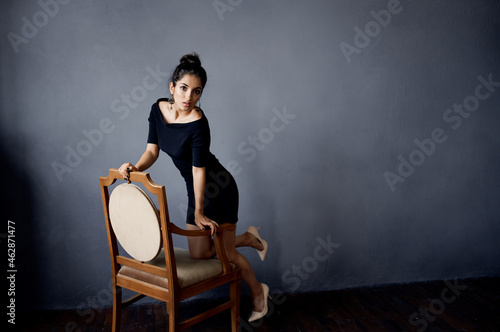 pretty woman in a black dress near the chair luxury fashion lifestyle studio