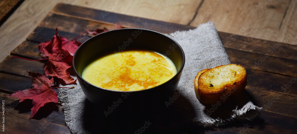 Pumpkin soup puree in a brown plate on a wooden table Pumpkin soup puree in a brown plate on a wooden table