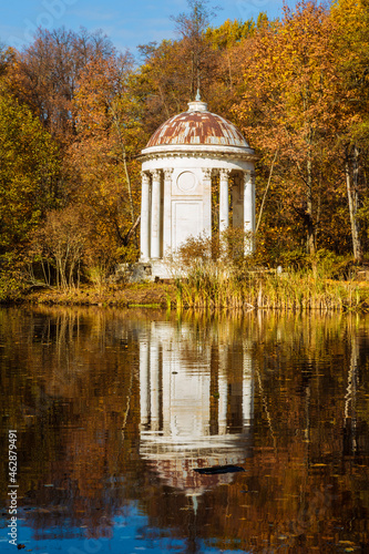 rotunda on the shore of a pond in autumn with reflection in the water