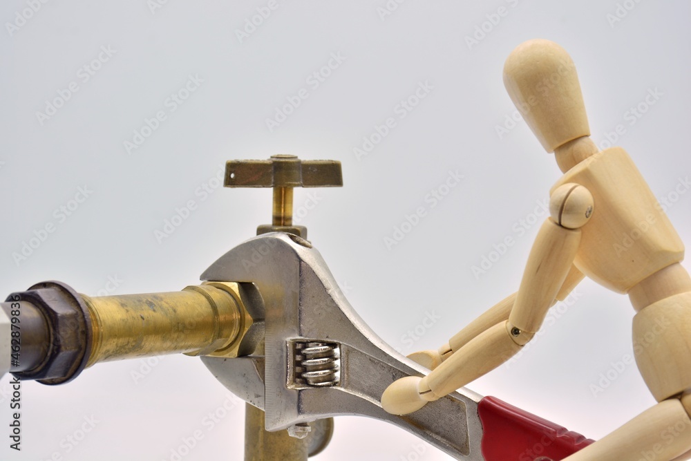 Muñeco de madera con una llave ajustable, apretando una tuerca de fontanería Muñeco de madera con una llave ajustable, apretando una tuerca de fontanería