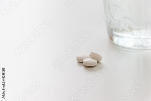 三粒の白い錠剤とグラスの水