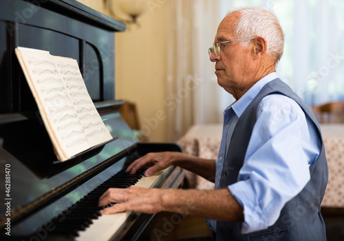 Grandfather is learning to play piano at home. Life after retirement concept