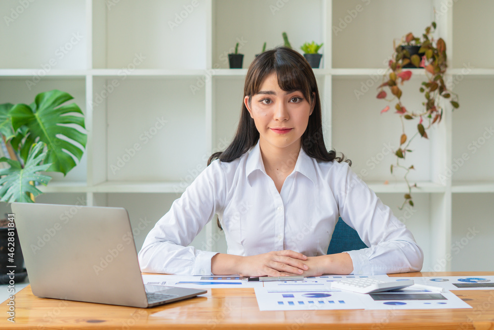 Confident woman sitting in office behind desk with laptop computer and documents. Confident woman sitting in office behind desk with laptop computer and documents.