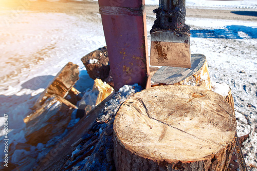 Sharp blade of electric wood splitter. Log splitter with wood and trunks. Wood splitter, industrial machine for split logs and wood. Winter season photo
