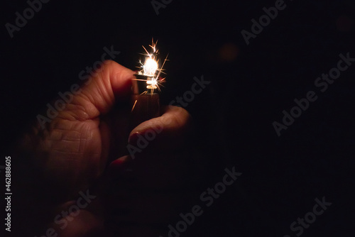 Sparks coming from lighter over black background.Womans hand,Flame and sparks coming from lighter.Selective focus.Copy space.