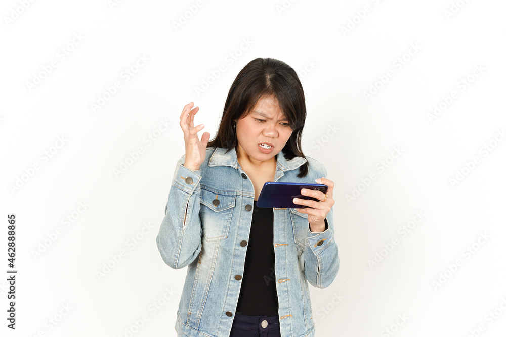 Playing Game on Phone With Angry Face of Beautiful Asian Woman Wearing Jeans Jacket and black shirt Isolated On White Background Playing Game on Phone With Angry Face of Beautiful Asian Woman Wearing Jeans Jacket and black shirt Isolated On White Background