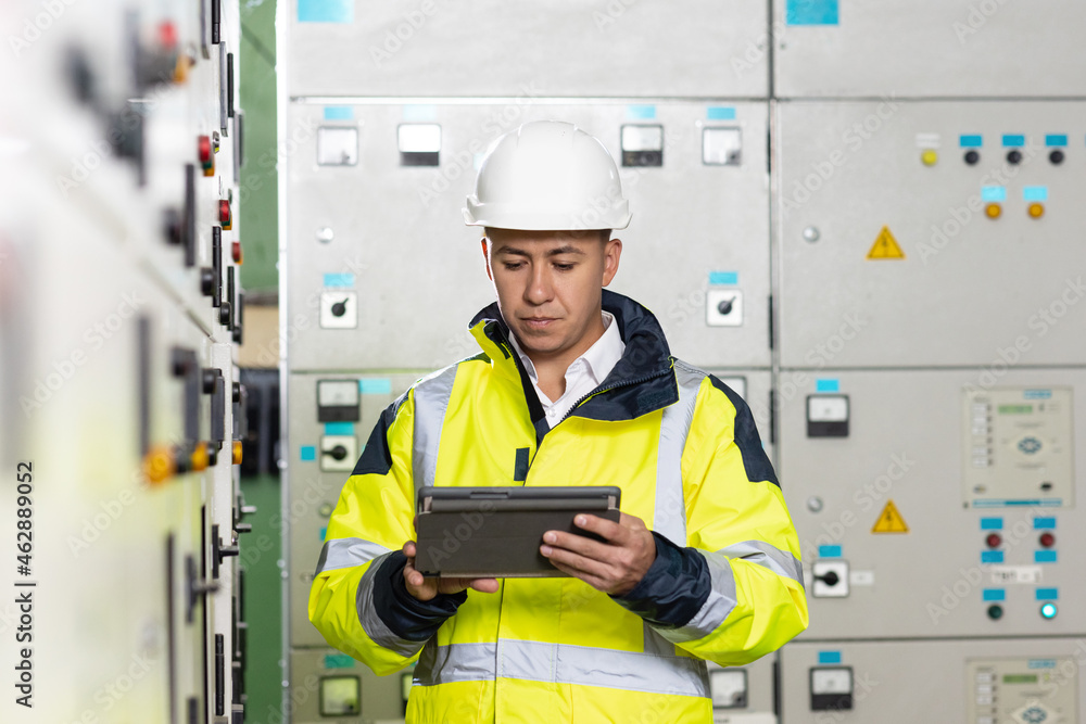 Technician inspect to control panel screen system for generate electricity of factory in manufacture industrial. Man electrical engineer hold tablet monitoring electrical system in control room Technician inspect to control panel screen system for generate electricity of factory in manufacture industrial. Man electrical engineer hold tablet monitoring electrical system in control room