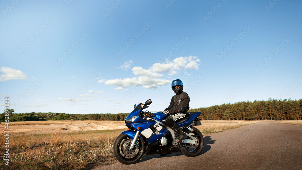 Biker man on a motorcycle in a leather jacket and helmet looks at the road Biker man on a motorcycle in a leather jacket and helmet looks at the road