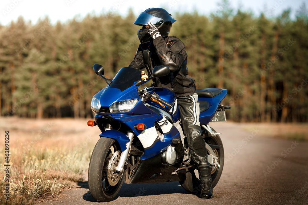Biker man on a motorcycle in a leather jacket and helmet looks at the road Biker man on a motorcycle in a leather jacket and helmet looks at the road
