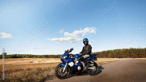 Biker man on a motorcycle in a leather jacket and helmet looks at the road