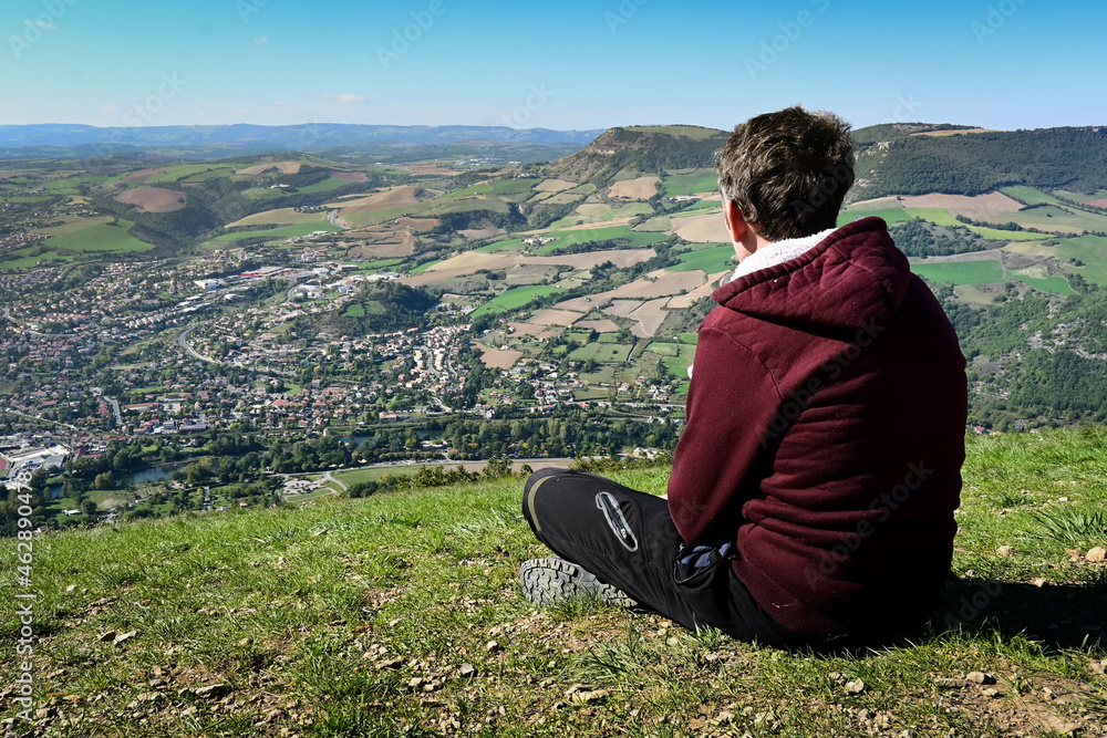 homme qui regarde l'horizon assis en haut d'une montagne