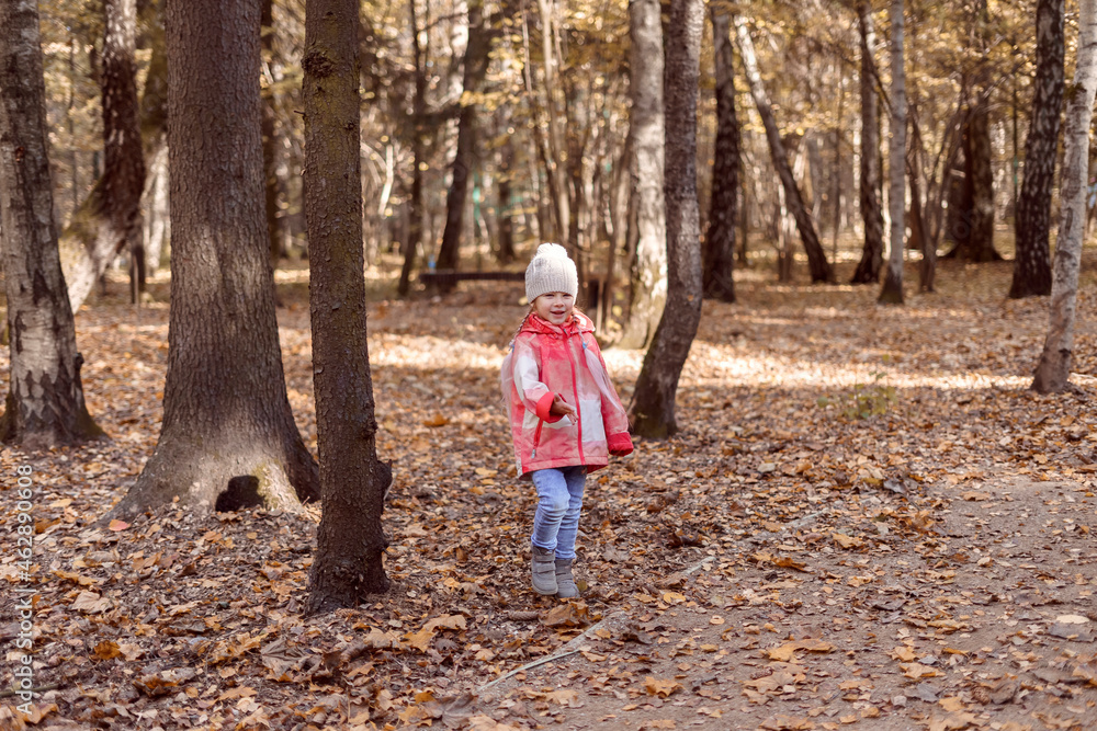 5 year old little girl in an orange jacket and jeans in autumn park. 5 year old little girl in an orange jacket and jeans in autumn park.
