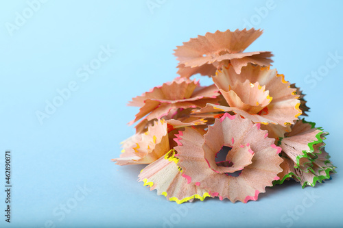 Pile of colorful pencil shavings on light blue background, closeup. Space for text