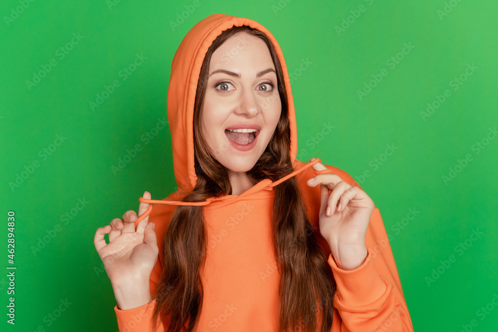 Fototapeta premium Portrait of charming excited funky lady play with clothes wear hood on green background